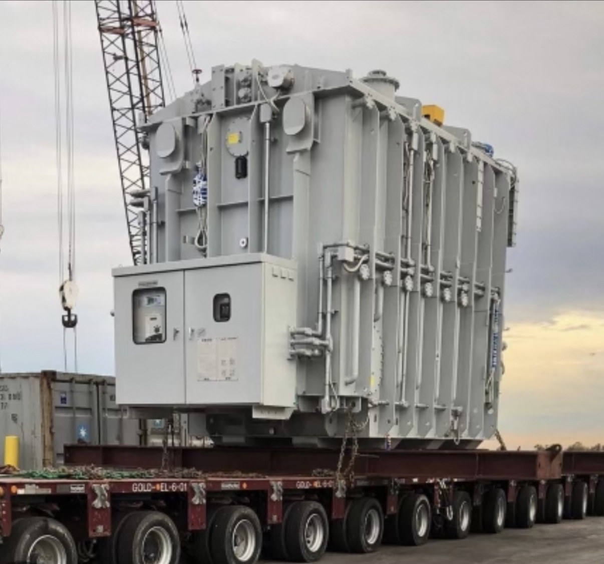 Large gray power transformer secured on a multi-axle transport trailer